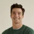 Portrait of a smiling man wearing a green sweater.