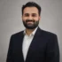 Bhargav Nanda- Founder - Prana Accounting Professional headshot of a man wearing a black suit and white shirt against a neutral background.