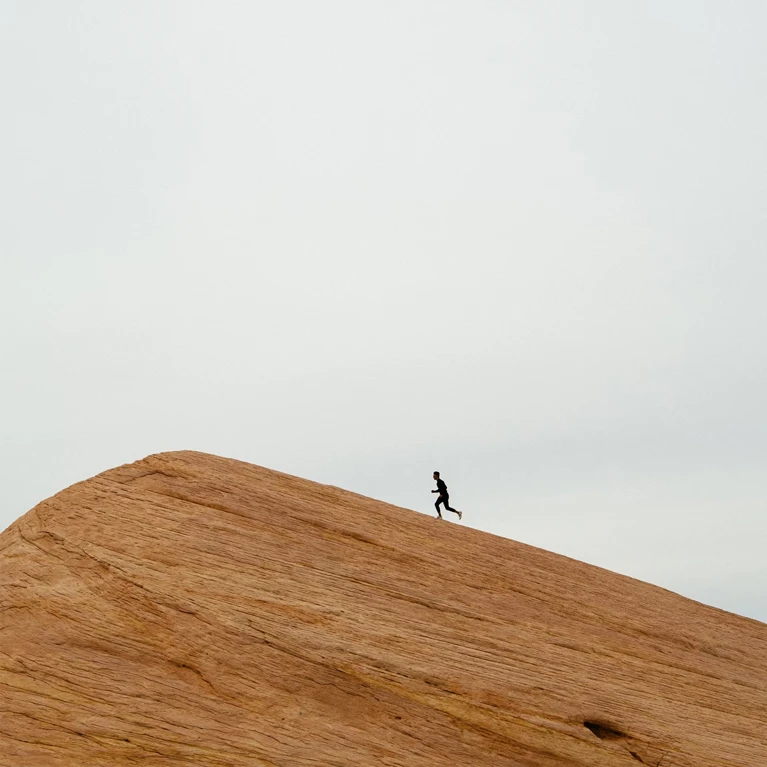 Person walking alone on a large desert sand dune.